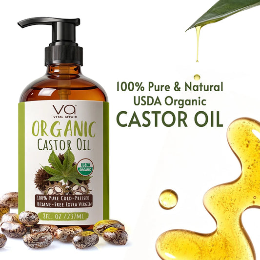 Bottle of Vital Affair Organic Castor Oil with pump, surrounded by castor beans and oil droplets on a white background.